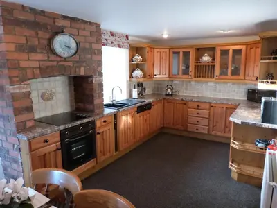 a kitchen with wooden cabinets and a clock on a brick wall at Ysgubor Illtyd in Dolgellau