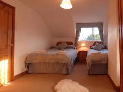 a bedroom with two beds and a window at Ysgubor Illtyd in Dolgellau