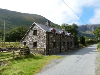 an old stone house on the side of a road at Troed yr Aran in Aber Cowarch