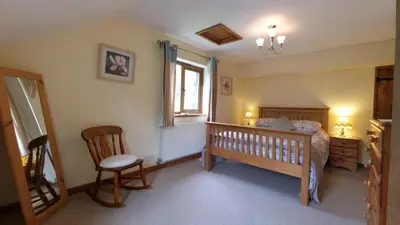 a bedroom with a bed and a chair and a window at Troed yr Aran in Aber Cowarch
