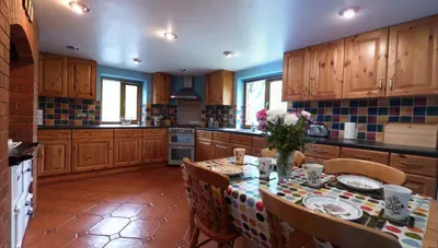 a kitchen with a table and chairs and a kitchen with wooden cabinets at Troed yr Aran in Aber Cowarch
