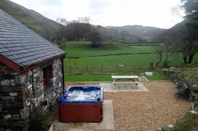 a picnic table next to a stone building with a picnic table at Troed yr Aran in Aber Cowarch