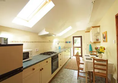 a kitchen with a stove and a table with chairs at Ty Clyd in Cross Inn