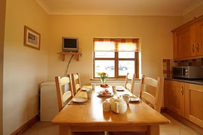 a kitchen with a wooden table with chairs and a dining room at Y Ddinas in Llanilar