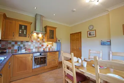 a kitchen with a wooden table and a dining room at Y Ddinas in Llanilar