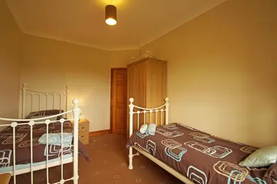 a bedroom with two beds and a wooden cabinet at Y Ddinas in Llanilar