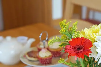 a table topped with cupcakes and a vase of flowers at Y Ddinas in Llanilar