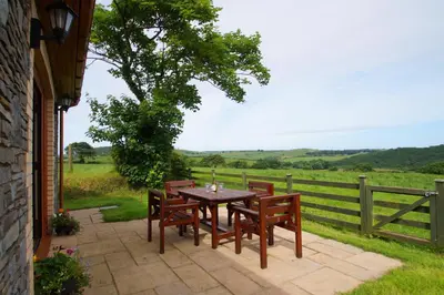a table and chairs on a patio with a fence at Y Ddinas in Llanilar