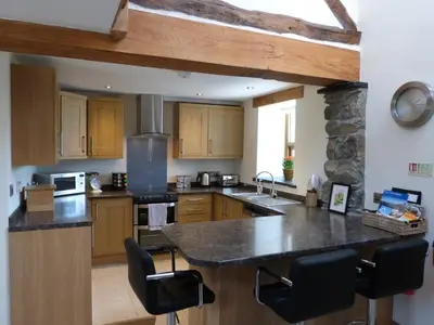 a large kitchen with wooden cabinets and a counter top at Ysgubor y Waun in Tywyn