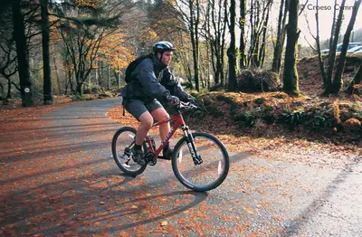 a man riding a bike down a road at Ysgubor y Waun in Tywyn