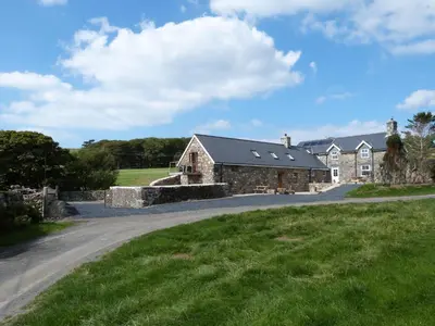 an old stone house with a road in front of it at Ysgubor y Waun in Tywyn