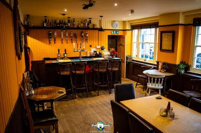 a bar in a restaurant with wooden tables and chairs at The Bear Inn in Llandovery
