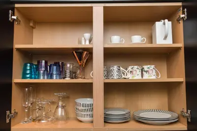 a wooden cabinet with plates and cups and dishes at Sea view Ar Lan y Mor LUXURY APARTMENT in Aberystwyth