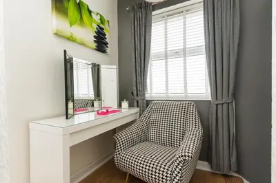 a bathroom with a chair next to a mirror at Sea view Ar Lan y Mor LUXURY APARTMENT in Aberystwyth
