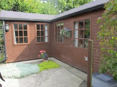 a large wooden shed with a door and windows at The Garden Lodge in Llynclys