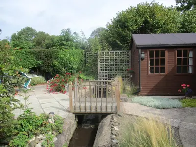 a garden with a gate and a small house at The Garden Lodge in Llynclys