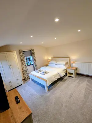 a large bedroom with a large bed and a table at The Garden Lodge in Llynclys