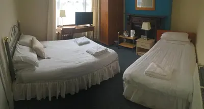 a hotel room with a large white bed and a desk at Four Seasons Budget in Aberystwyth
