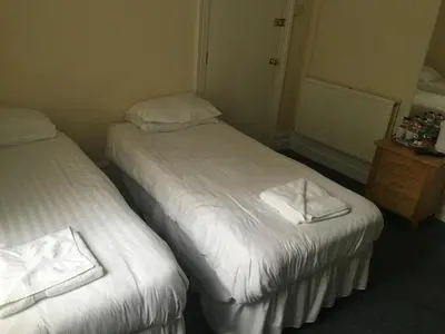a room with two beds and a wooden night stand at Four Seasons Budget in Aberystwyth