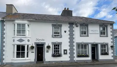 a white house with black doors and windows at Arosfa Harbourside Aberaeron in Aberaeron