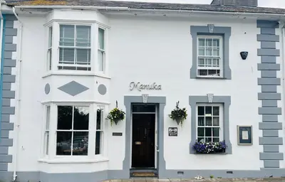 a white house with a black door and windows at Arosfa Harbourside Aberaeron in Aberaeron