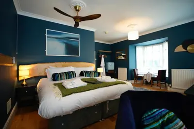 a bedroom with a large bed with blue walls at Arosfa Harbourside Aberaeron in Aberaeron