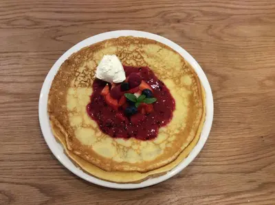 a plate of pancakes with fruit and ice cream on a table at Ty Mawr at Bethania B&B Rooms and Crumble Cottage in Llanon