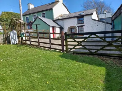 a wooden fence in front of a house at Ty Mawr at Bethania B&B Rooms and Crumble Cottage in Llanon