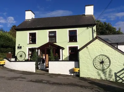 a green and white house with a black roof at Ty Mawr at Bethania B&B Rooms and Crumble Cottage in Llanon