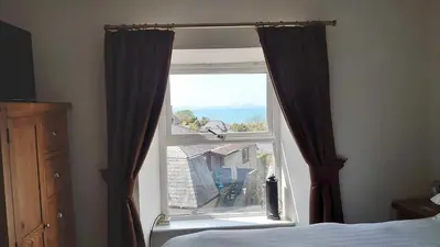 a bedroom window with a view of a house at Byrdir House in Harlech