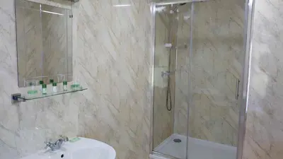 a bathroom with a shower with a sink and a glass shower stall at Byrdir House in Harlech