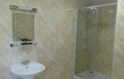 a bathroom with a glass shower and a sink at Byrdir House in Harlech