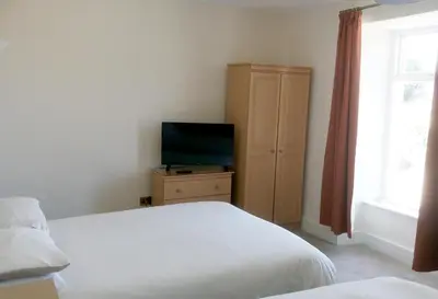 a bedroom with a bed and a television on a dresser at Byrdir House in Harlech