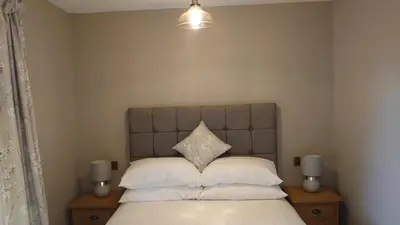 a bedroom with a bed with white sheets and pillows at Byrdir House in Harlech