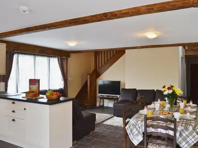 a kitchen and living room with a table and a couch at Llaethdy-Milkhouse in Talgarth