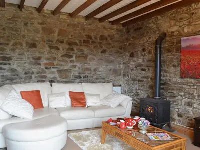 a living room with a white couch and a stove at Ty Coch Cottage in Dihewid