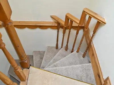 a staircase with wooden railings and a wooden stair case at Ty Coch Cottage in Dihewid