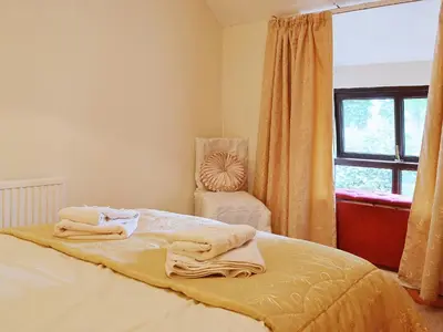 a bedroom with a bed and a chair and a window at Ty Coch Cottage in Dihewid