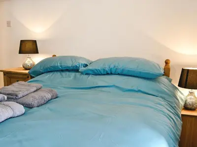 a bed with blue pillows and towels on it at Pendref in Trawsfynydd