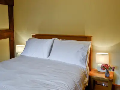 a bedroom with a bed with white sheets and two lamps at Mill Cottage in Peterchurch