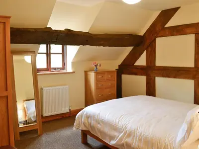 a bedroom with a large bed and a dresser at Mill Cottage in Peterchurch