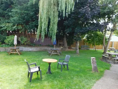 a table and chairs in a yard with picnic tables and benches at The Railway Inn in Forden