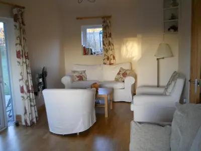 a living room with white chairs and a couch at Ty'r Afon - River Cottage in Bala