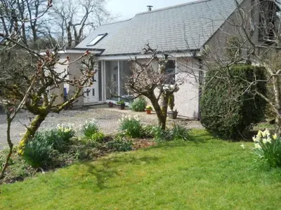a white house with a garden and a yard with a house at Ty'r Afon - River Cottage in Bala