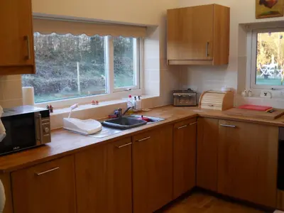 a kitchen with wooden cabinets and a sink and a microwave at Ty'r Afon - River Cottage in Bala