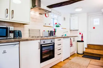 a kitchen with white cabinets and a stove top oven at Thursdays Corner Tudor Cottage in Church Stretton