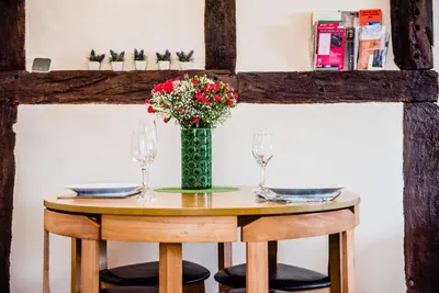 a wooden table with a vase of flowers on it at Thursdays Corner Tudor Cottage in Church Stretton