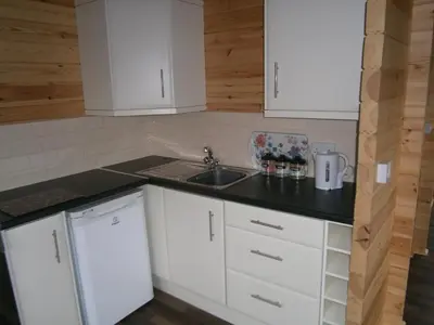 a kitchen with white cabinets and a sink at Long Mountain Centre Log Cabins in Meadowtown