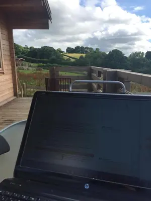 a laptop computer sitting on a table on a patio at Long Mountain Centre Log Cabins in Meadowtown