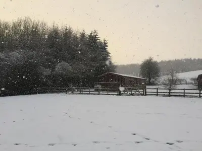 a snow covered field with a barn in the background at Long Mountain Centre Log Cabins in Meadowtown